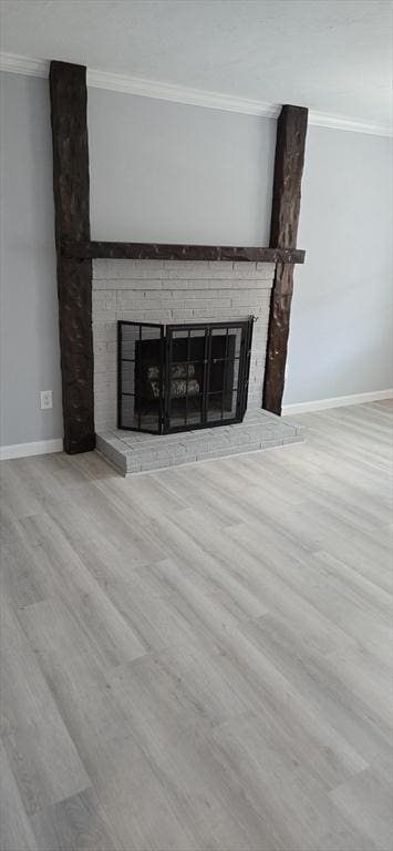 unfurnished living room with baseboards, a brick fireplace, wood finished floors, and crown molding