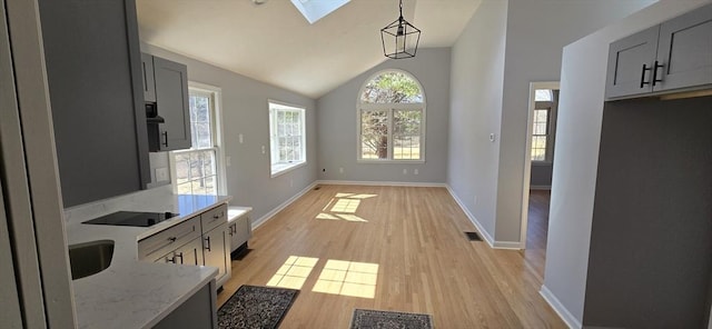 dining area with baseboards, vaulted ceiling with skylight, visible vents, and light wood-style floors