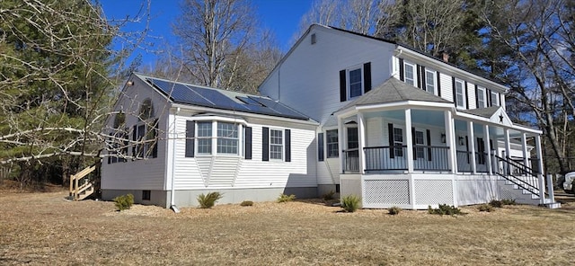 view of front of property featuring covered porch and solar panels