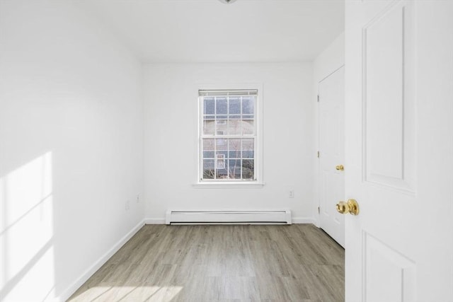 empty room featuring a baseboard radiator, baseboards, and wood finished floors