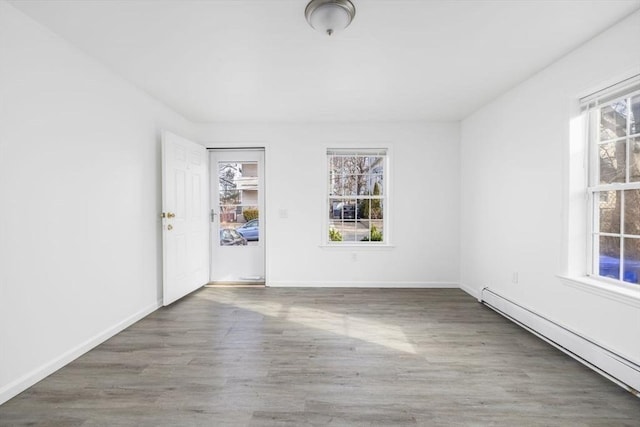 spare room with a healthy amount of sunlight, wood finished floors, baseboards, and a baseboard radiator