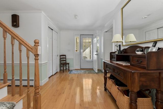 entrance foyer featuring light hardwood / wood-style floors, ornamental molding, and a baseboard radiator