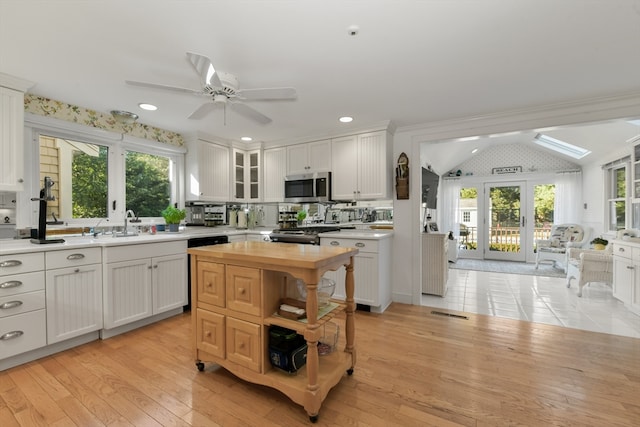 kitchen featuring vaulted ceiling, white cabinetry, and light hardwood / wood-style floors