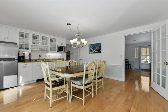 dining room with sink, light hardwood / wood-style flooring, and a notable chandelier