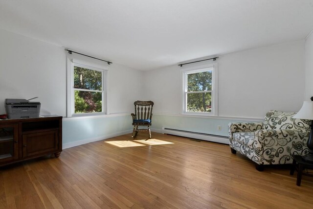 sitting room featuring a wealth of natural light, baseboard heating, and light wood-type flooring