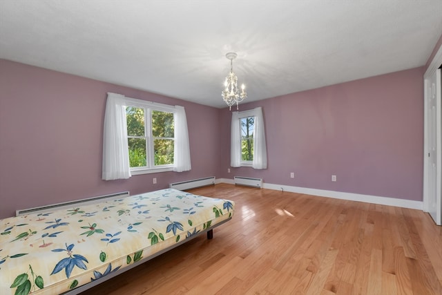 unfurnished bedroom with a notable chandelier, a baseboard heating unit, and light wood-type flooring