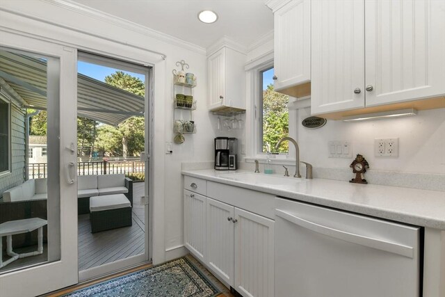 kitchen featuring sink, ornamental molding, white cabinetry, and dishwashing machine