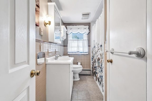 bathroom featuring tile walls, toilet, tile patterned floors, a baseboard heating unit, and vanity