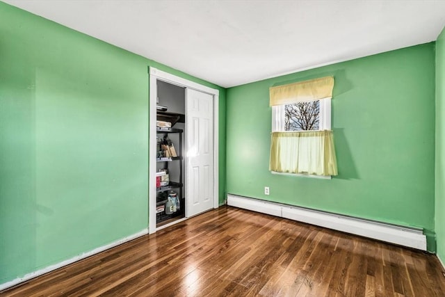 unfurnished bedroom with dark hardwood / wood-style flooring, a baseboard radiator, and a closet