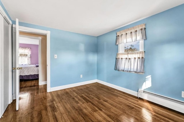 spare room with a baseboard heating unit and hardwood / wood-style flooring