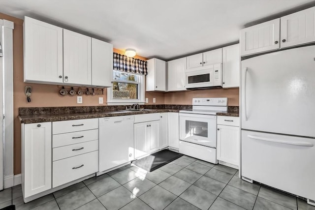 kitchen featuring sink, dark tile patterned floors, white appliances, and white cabinetry