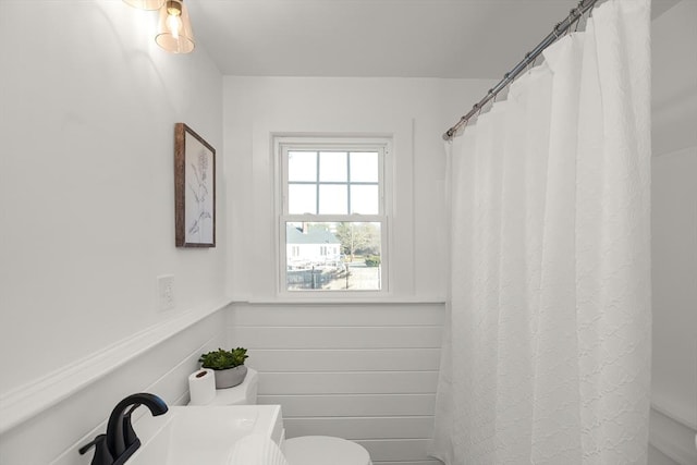 bathroom featuring wood walls, sink, and toilet