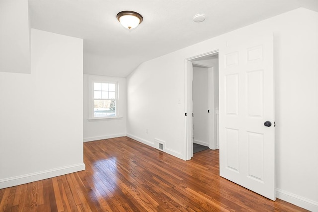 empty room with dark hardwood / wood-style floors and lofted ceiling