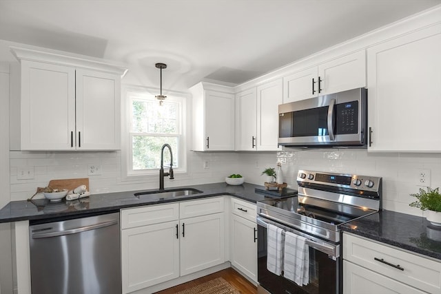 kitchen featuring white cabinets, decorative light fixtures, stainless steel appliances, and sink