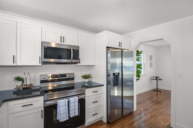 kitchen featuring backsplash, dark hardwood / wood-style flooring, white cabinets, and appliances with stainless steel finishes