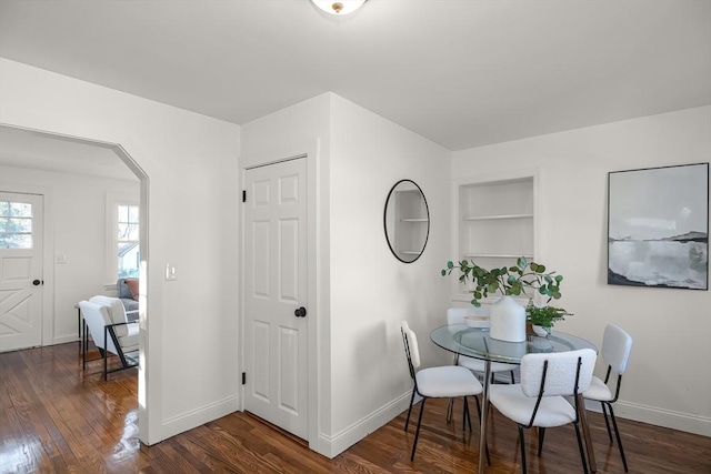 dining area featuring built in shelves and dark hardwood / wood-style floors