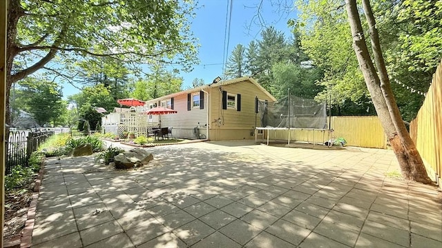 9 Willow Rd, Holbrook, MA 02343 - back of house featuring a trampoline, a patio area, and a fenced backyard