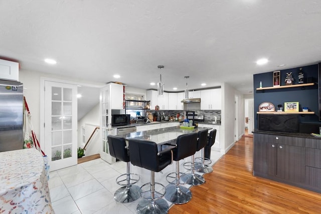 9 Willow Rd, Holbrook, MA 02343 - kitchen featuring black microwave, white cabinets, stainless steel fridge, a kitchen breakfast bar, and a kitchen island