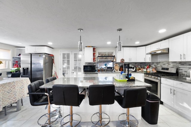 9 Willow Rd, Holbrook, MA 02343 - kitchen with stainless steel appliances, under cabinet range hood, stone counters, a sink, and decorative backsplash