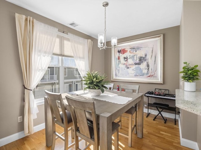 dining space with light hardwood / wood-style flooring and a chandelier