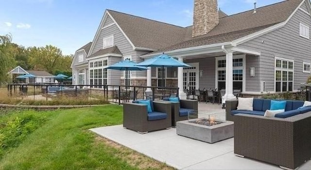 back of house featuring a lawn, a patio area, and an outdoor living space with a fire pit