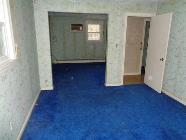 unfurnished room featuring an AC wall unit, dark carpet, and baseboard heating