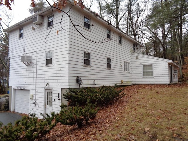 rear view of house with a garage and an AC wall unit