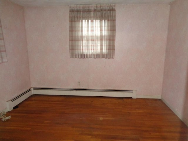 spare room featuring dark wood-type flooring and baseboard heating