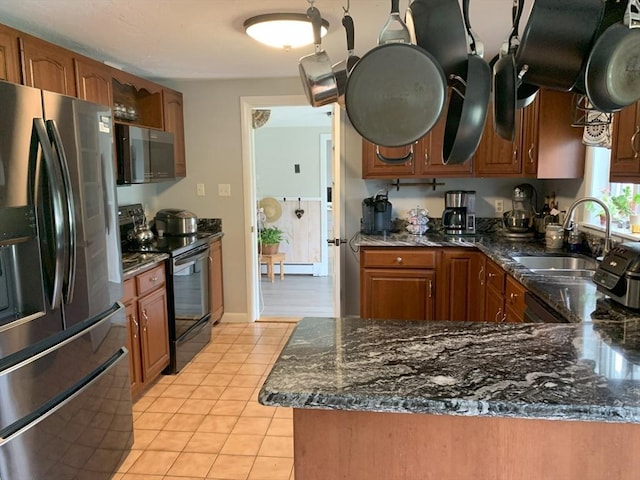 77 Westwood Pkwy, Southbridge, MA 01550 - kitchen with stainless steel appliances, light tile patterned floors, brown cabinetry, and dark stone countertops