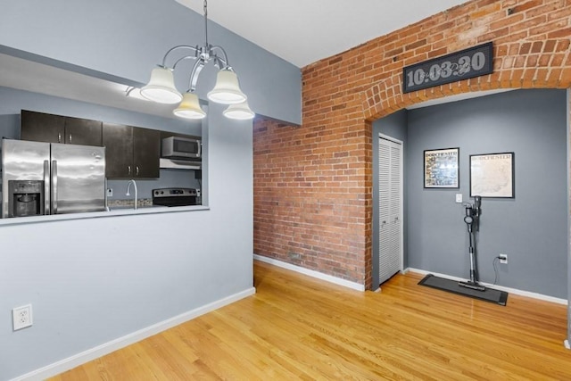 80 Beaumont St Unit 101, Boston, MA 02124 - kitchen with stainless steel appliances, brick wall, light wood-style floors, a chandelier, and hanging light fixtures