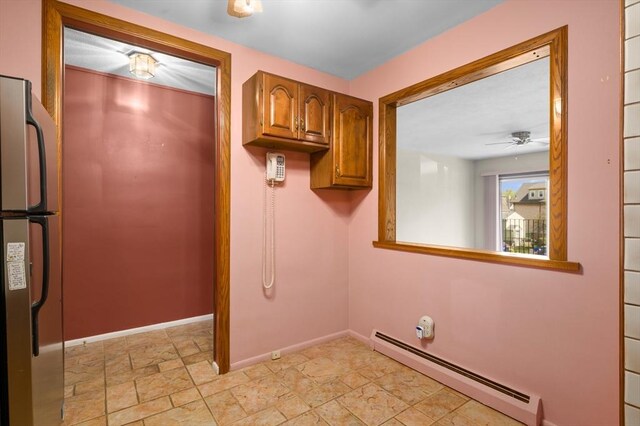 laundry area featuring baseboards, stone finish flooring, ceiling fan, and baseboard heating
