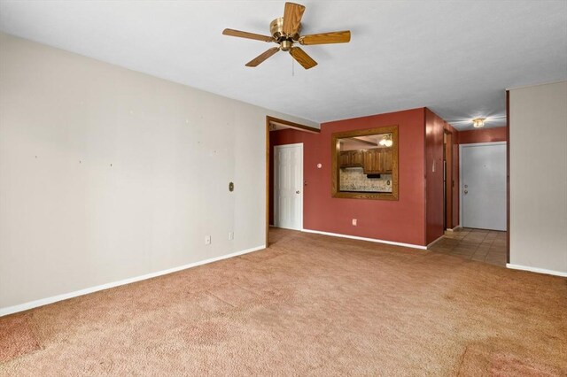 spare room with carpet floors, baseboards, and a ceiling fan