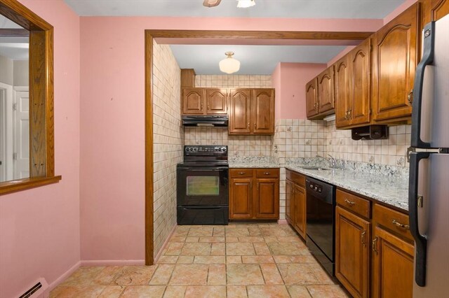 kitchen with brown cabinetry, a sink, a baseboard radiator, black appliances, and under cabinet range hood
