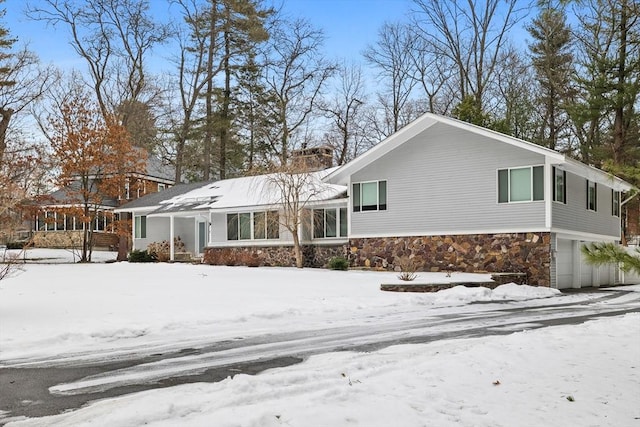 exterior space featuring a garage, stone siding, and a chimney