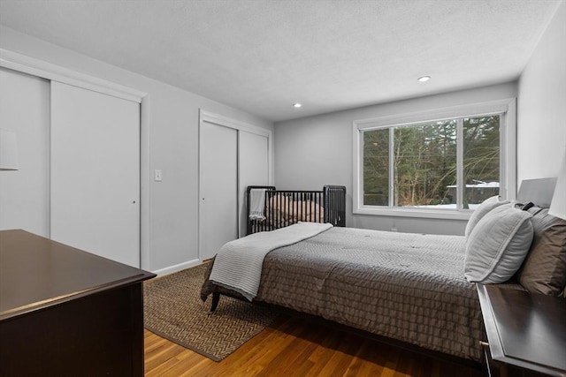 bedroom featuring recessed lighting, multiple closets, a textured ceiling, and wood finished floors