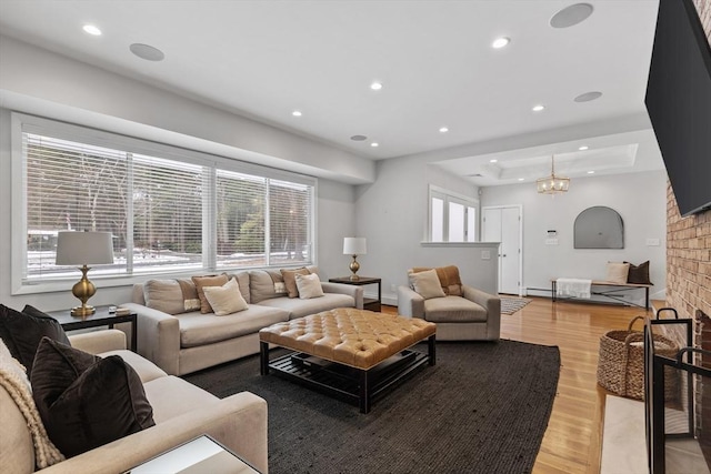 living room featuring a raised ceiling, a fireplace, light wood-style floors, and a wealth of natural light