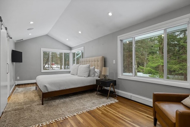 bedroom with wood finished floors, baseboards, a baseboard radiator, vaulted ceiling, and a barn door