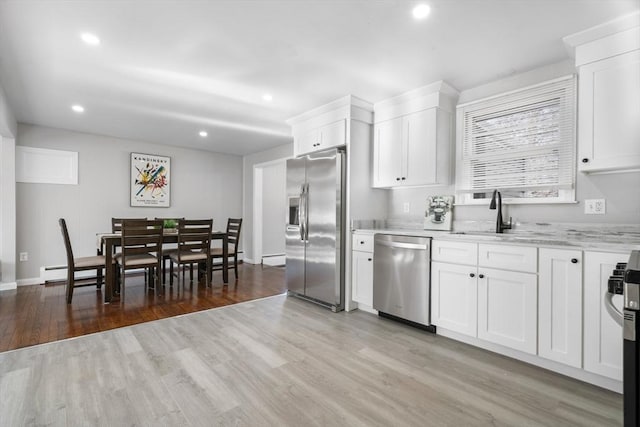 kitchen with white cabinetry, sink, light stone counters, light hardwood / wood-style floors, and stainless steel appliances