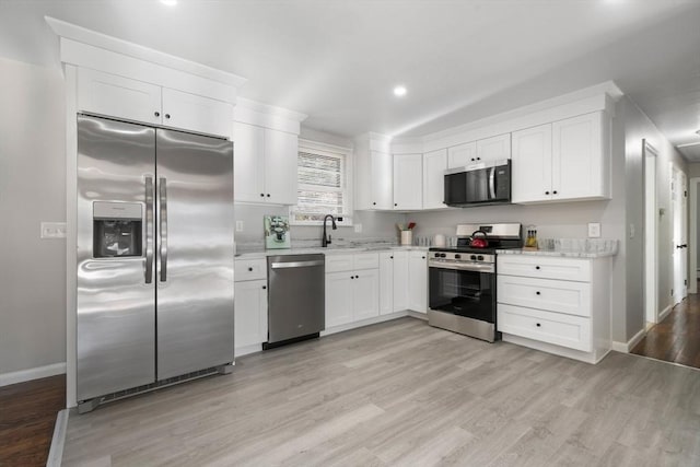 kitchen featuring sink, stainless steel appliances, light hardwood / wood-style floors, and white cabinets