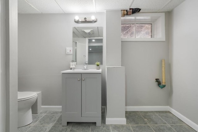 bathroom with a paneled ceiling, vanity, toilet, and tile patterned flooring