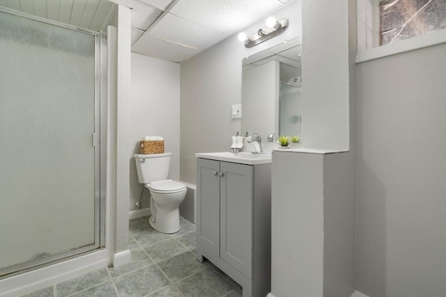 bathroom featuring vanity, a paneled ceiling, toilet, and a shower with shower door