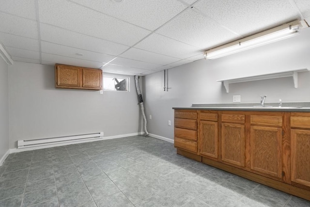 basement featuring a baseboard radiator, sink, and a paneled ceiling