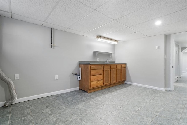 basement with light tile patterned floors, sink, and a drop ceiling