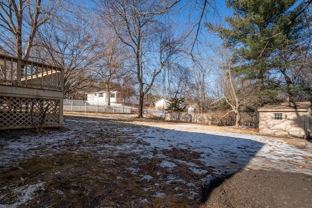 yard layered in snow featuring a deck and a shed