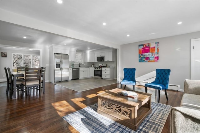 living room with dark hardwood / wood-style flooring, sink, and a baseboard heating unit