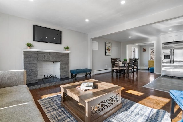 living room featuring baseboard heating, a fireplace, and dark wood-type flooring