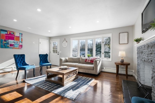 living room featuring a stone fireplace, dark hardwood / wood-style floors, and baseboard heating