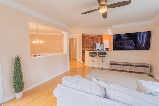 living room featuring light wood finished floors, ceiling fan with notable chandelier, crown molding, and baseboards