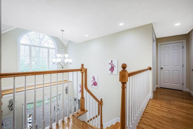 hallway featuring an inviting chandelier, an upstairs landing, wood finished floors, and baseboards