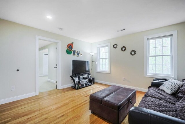living area featuring visible vents, light wood-style flooring, and a healthy amount of sunlight